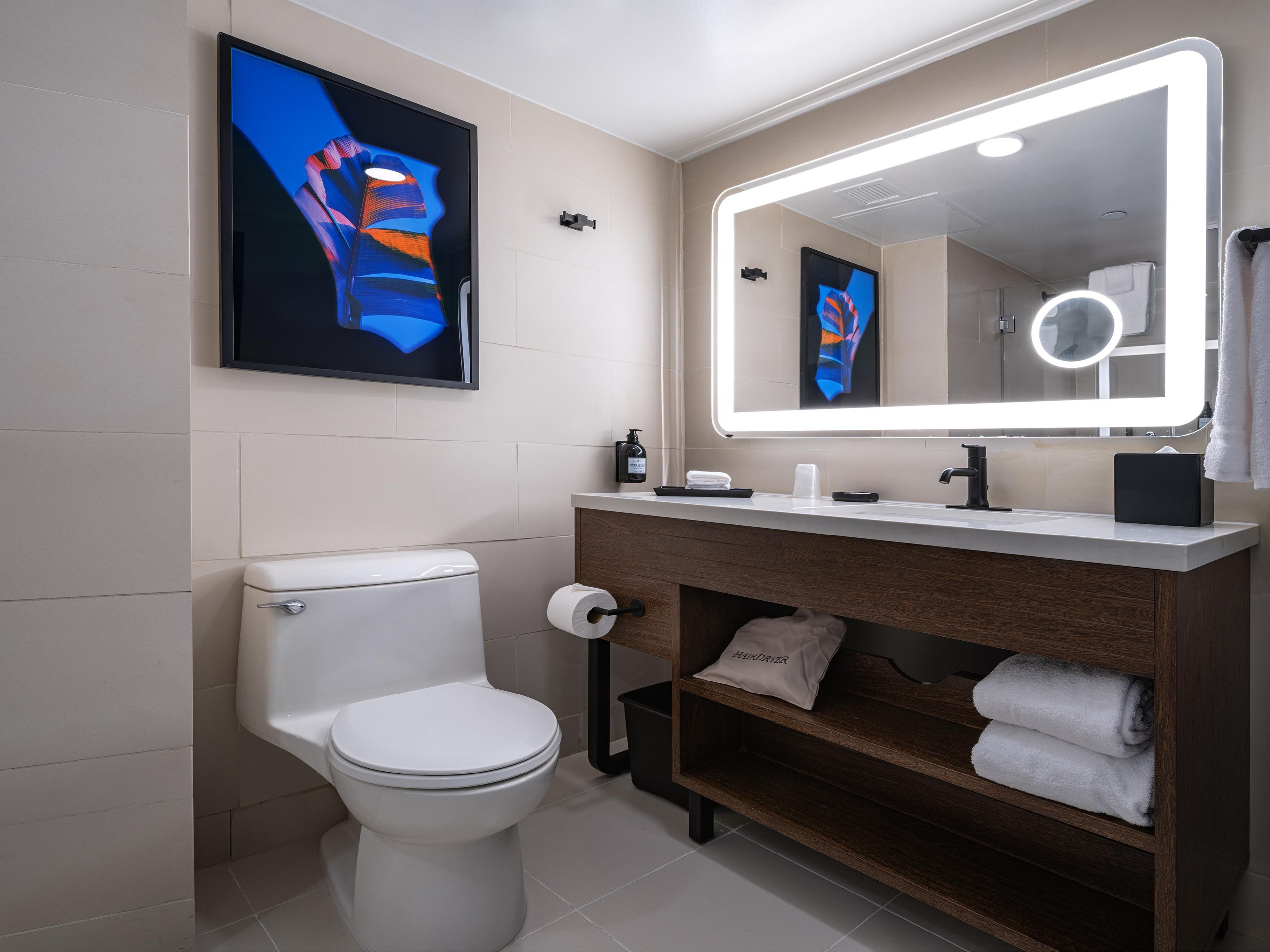 Ein modernes Badezimmer mit Toilette, Waschtisch und Spiegel sowie einem Handtuchhalter.