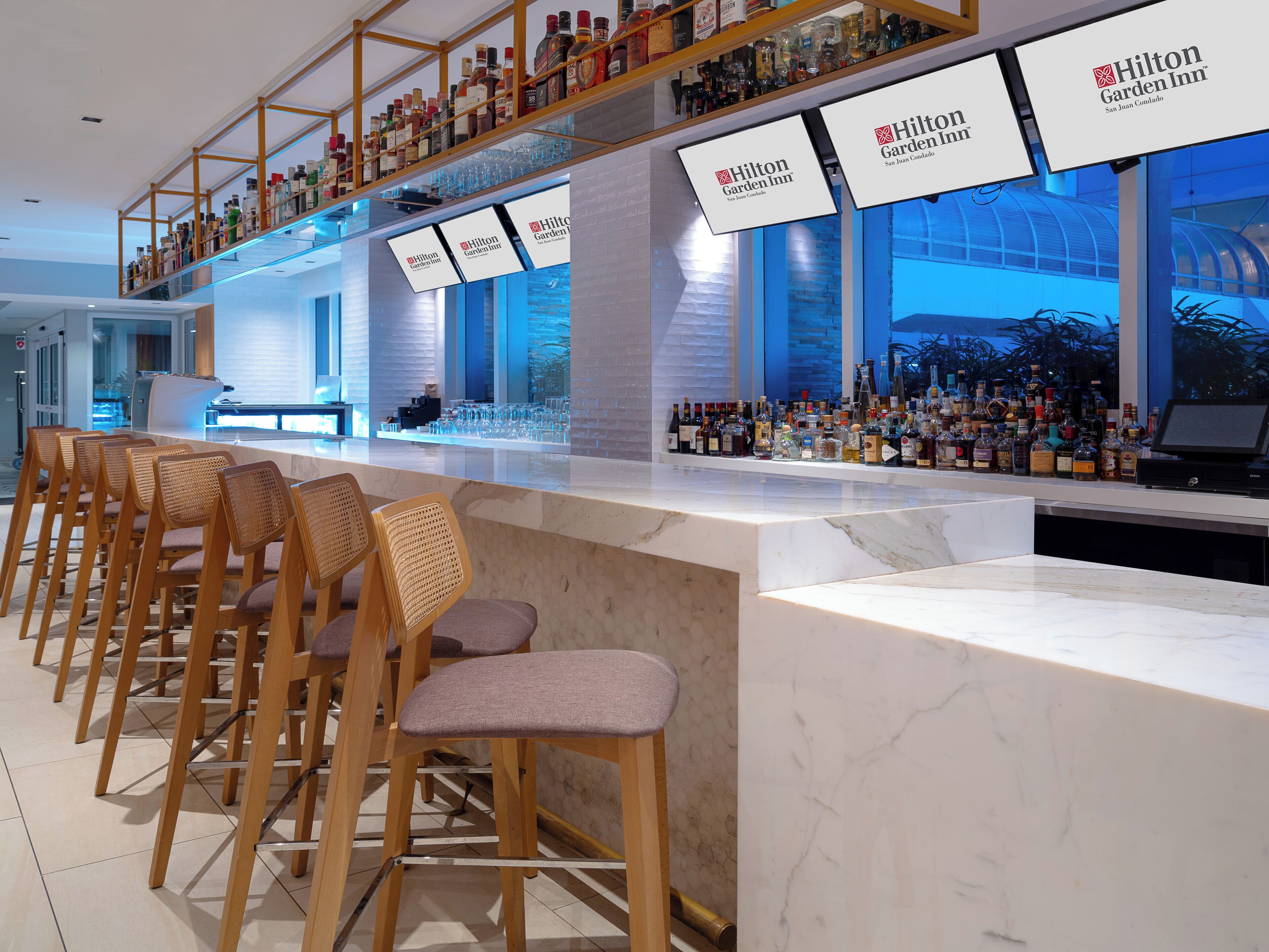 Zona de bar con diversas opciones de asientos y una variedad de botellas de licores.