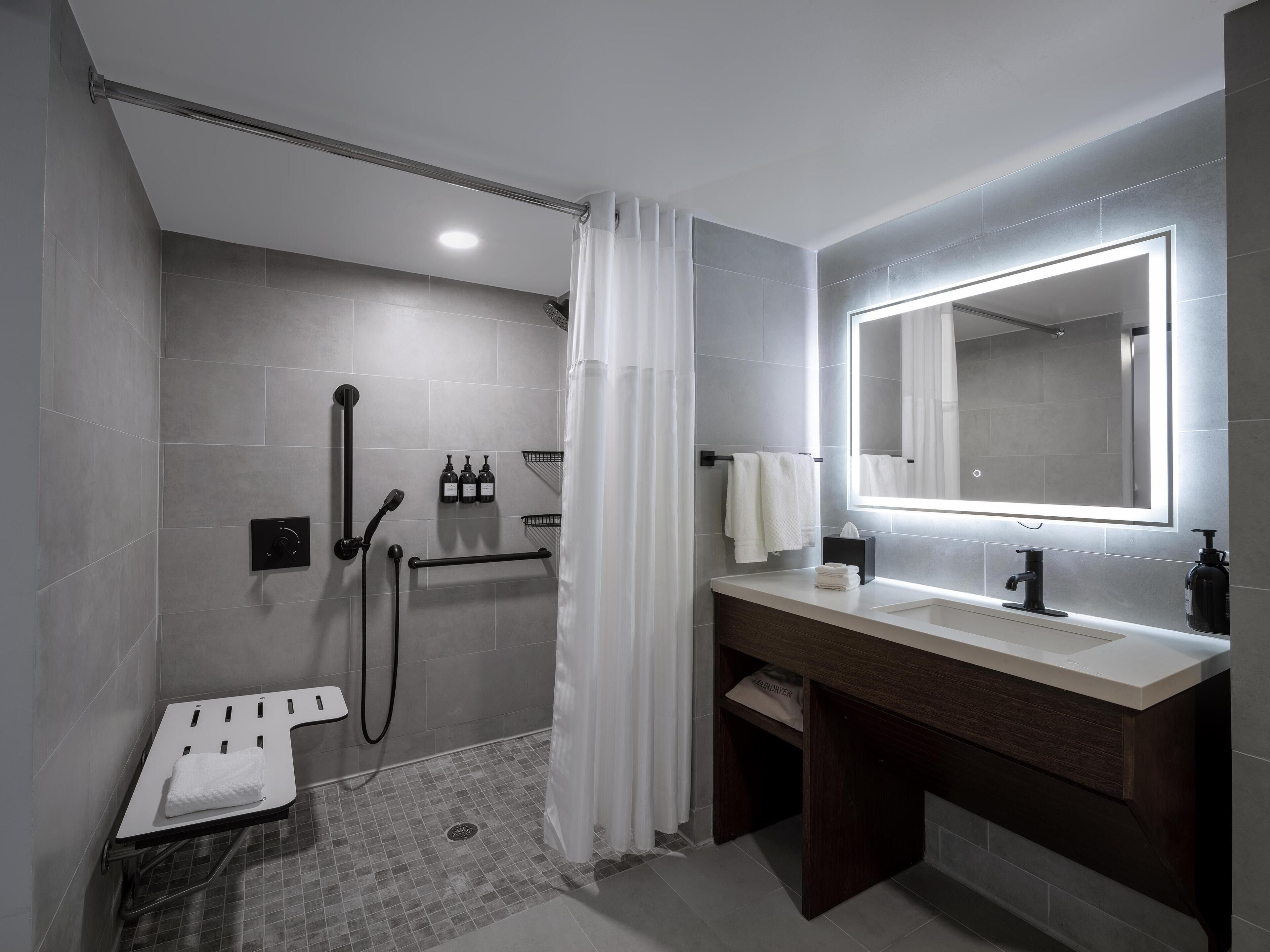 Une salle de bain moderne équipée d’une douche, d’un meuble-lavabo avec un miroir et d’un porte-serviettes.