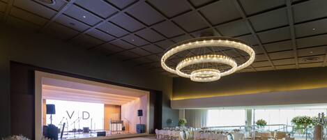 A spacious hall with tiered seating, a stage with musical instruments, and a chandelier.