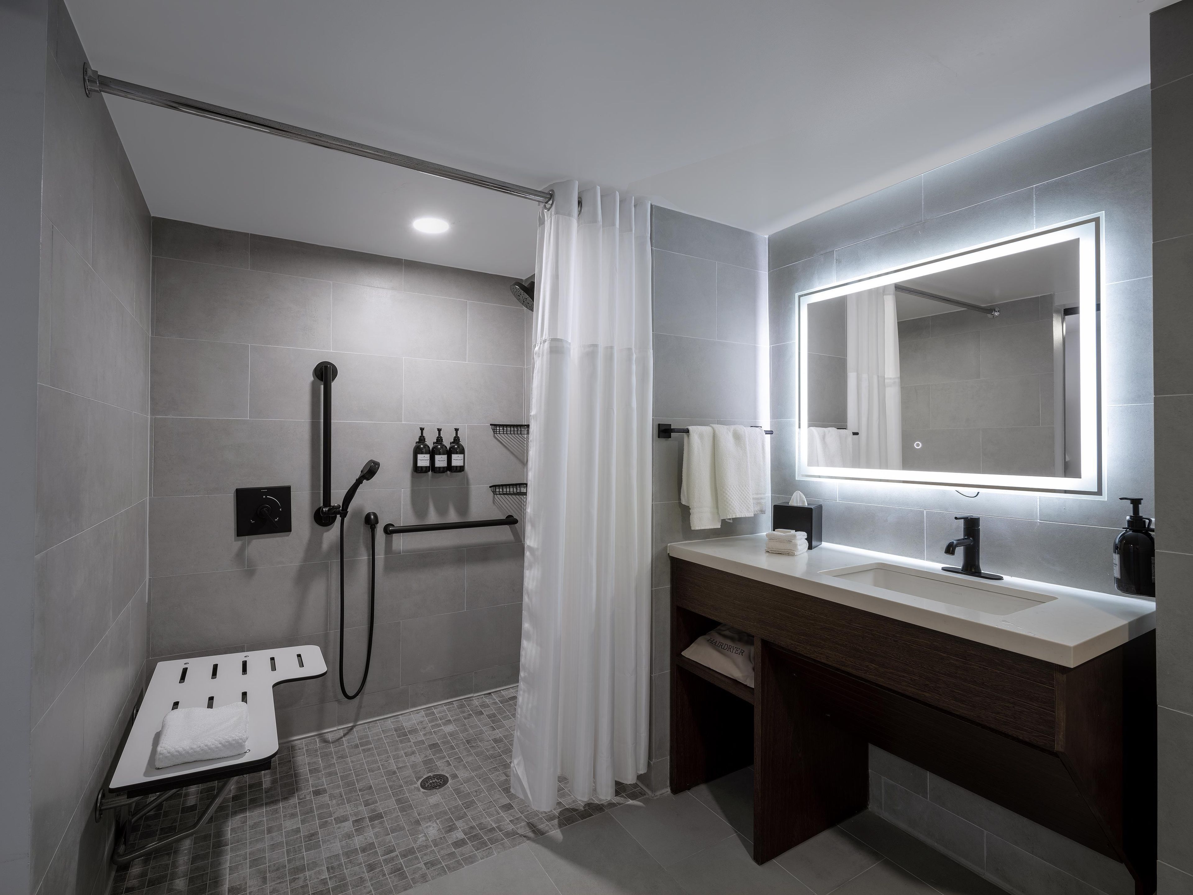 A modern bathroom with a shower, a vanity with a mirror, and a towel rack.