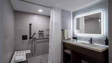 A modern bathroom with a shower, a vanity with a mirror, and a towel rack.