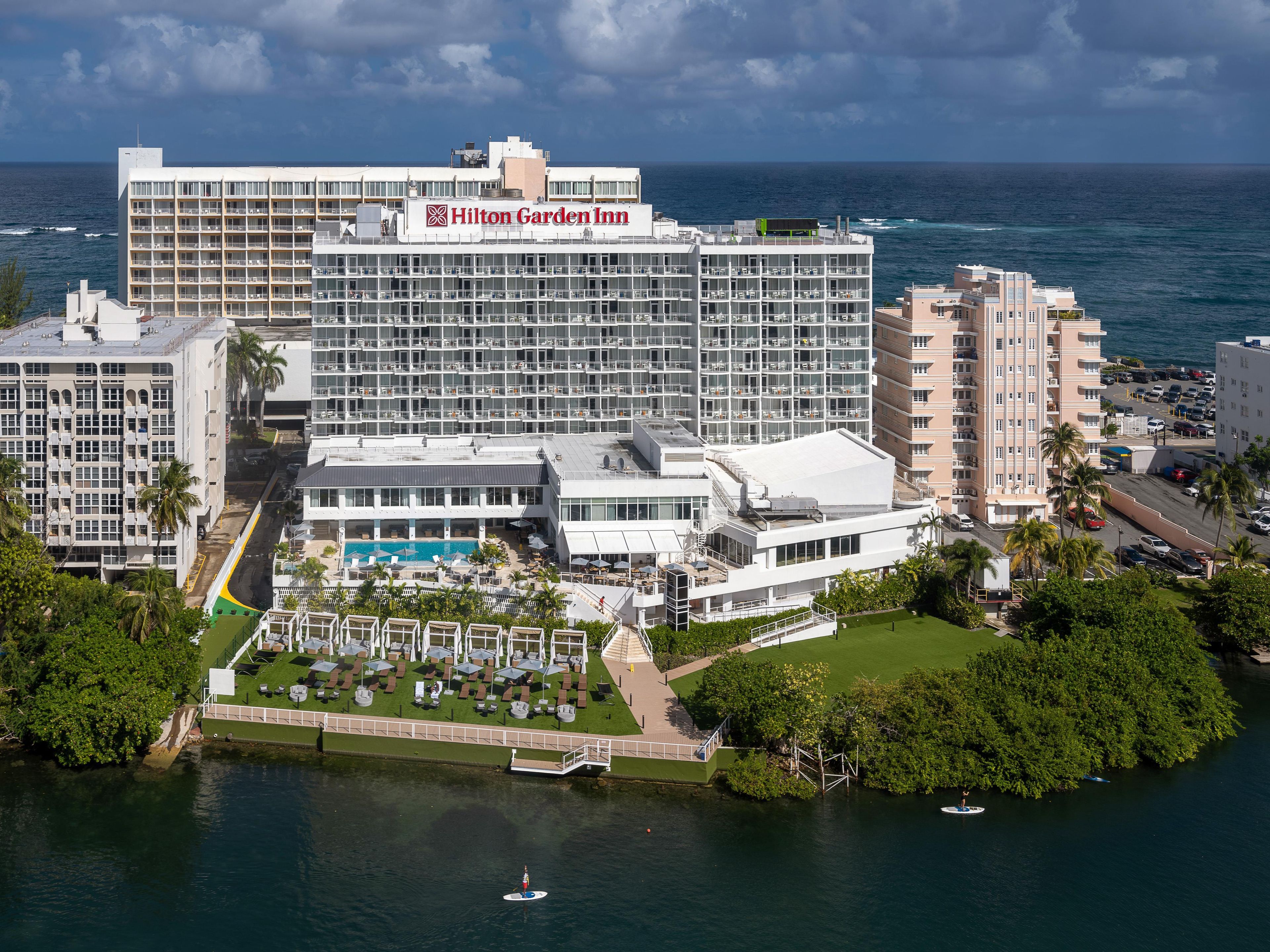 A large hotel with multiple floors, a swimming pool, and a view of the ocean.