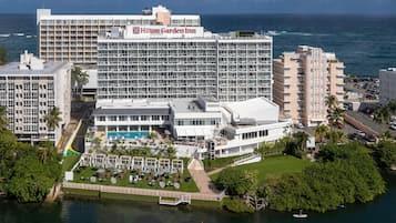 A large hotel with multiple floors, a swimming pool, and a view of the ocean.