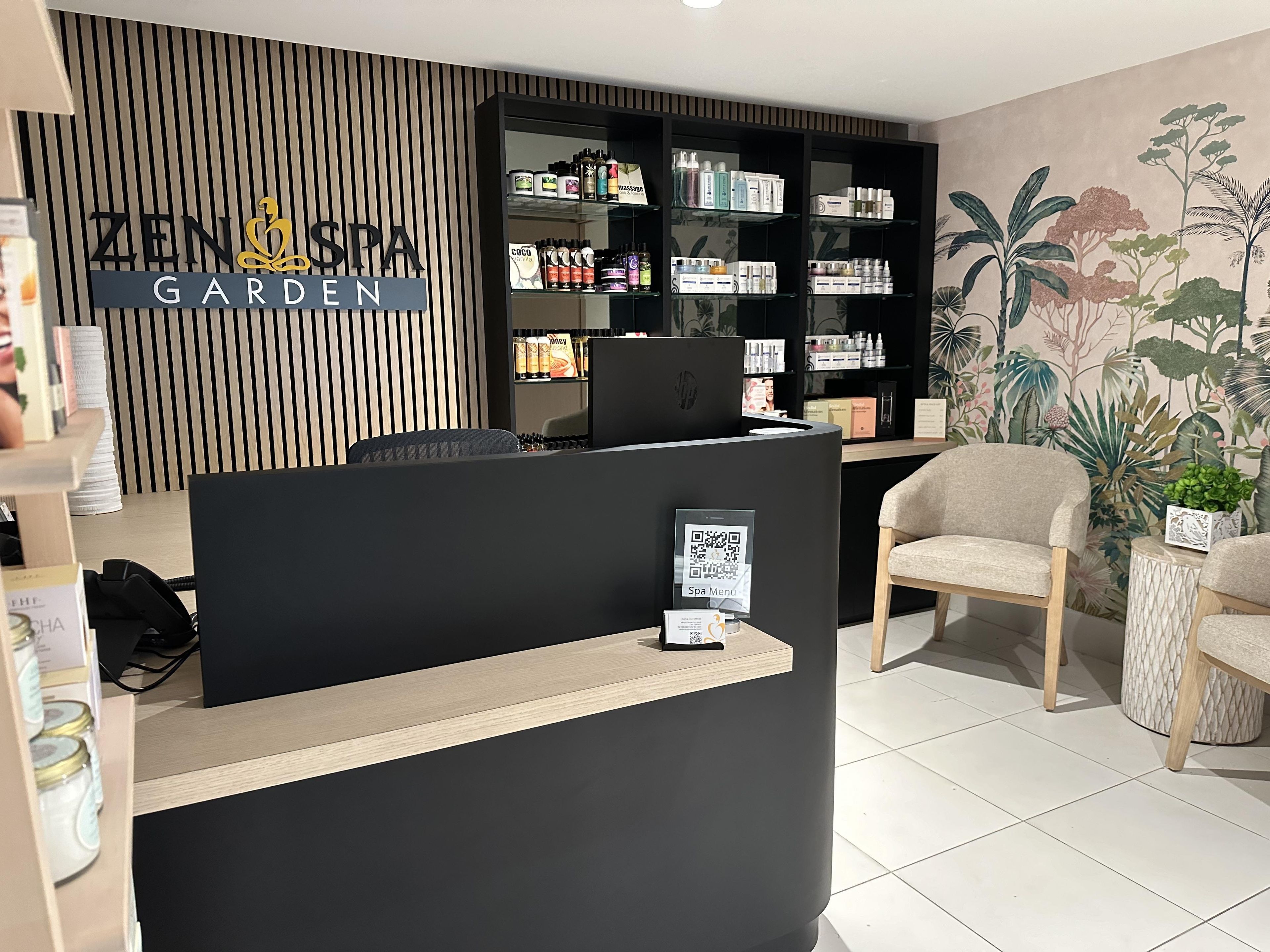 A reception area with a black reception desk, a wooden slat wall, and a shelf with various products.