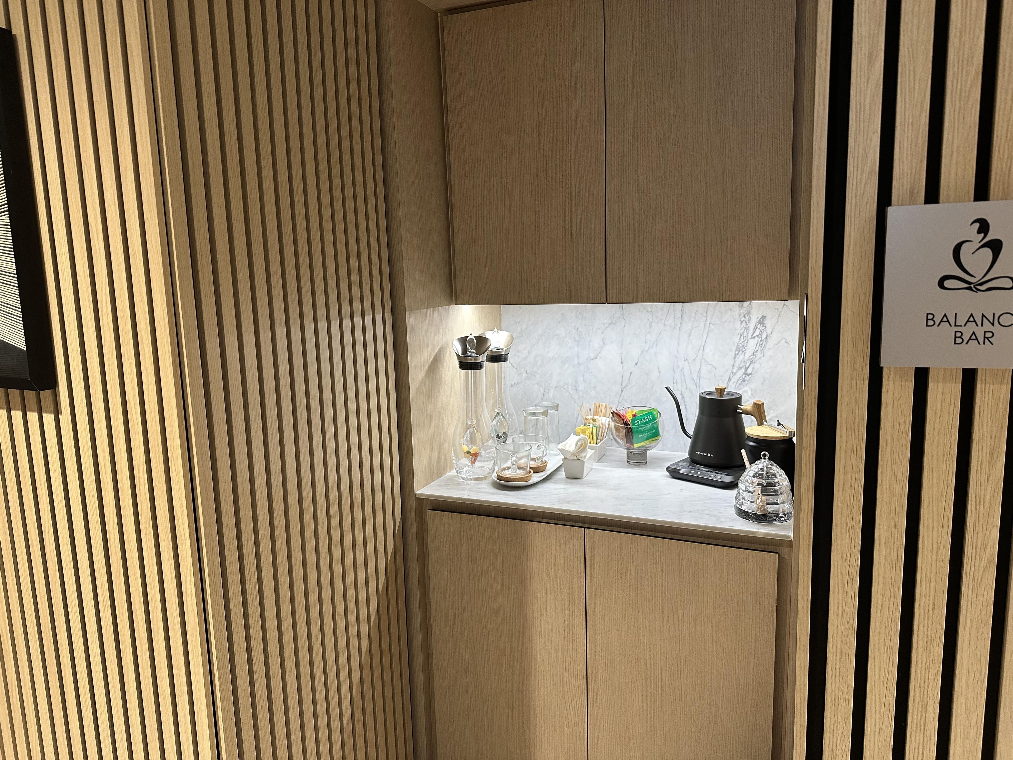 A modern kitchen area with a marble countertop, a coffee machine, and a sign for 'BALANCE BAR'.