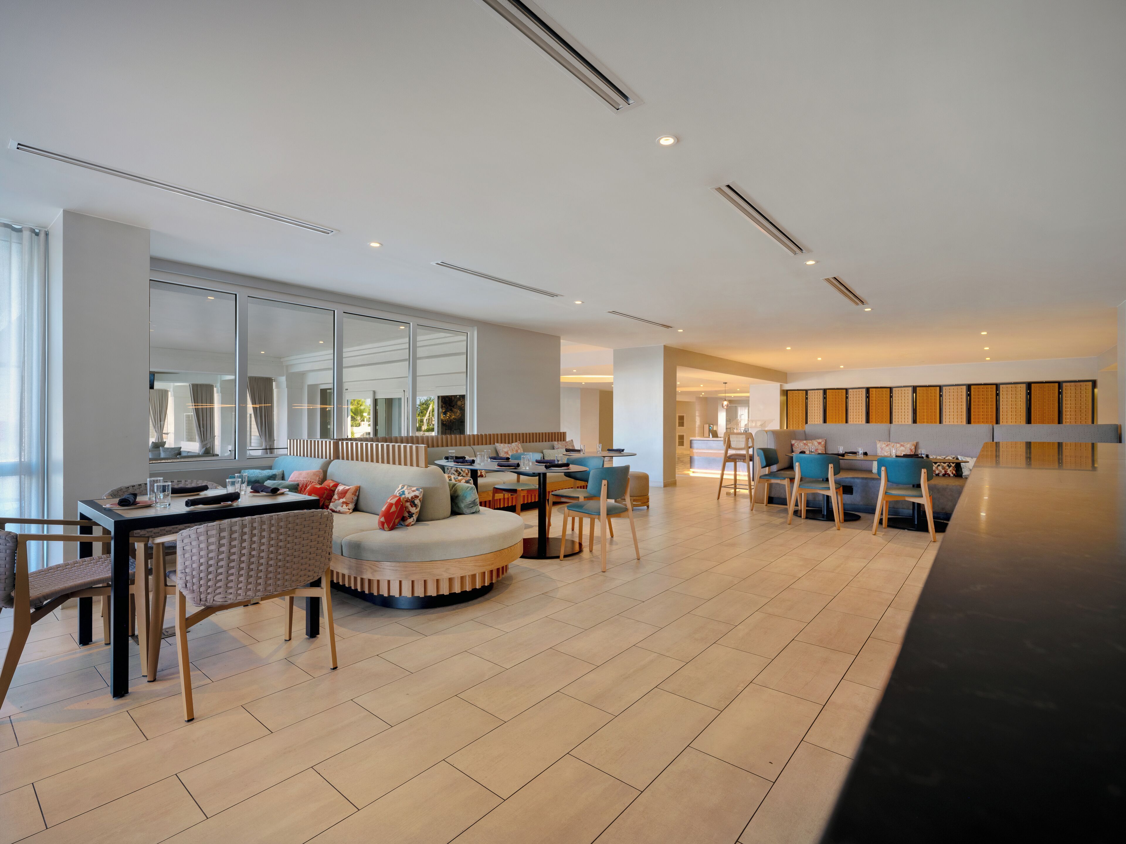 Un moderno vestíbulo de hotel con un área de descanso, un comedor y un mostrador de recepción.