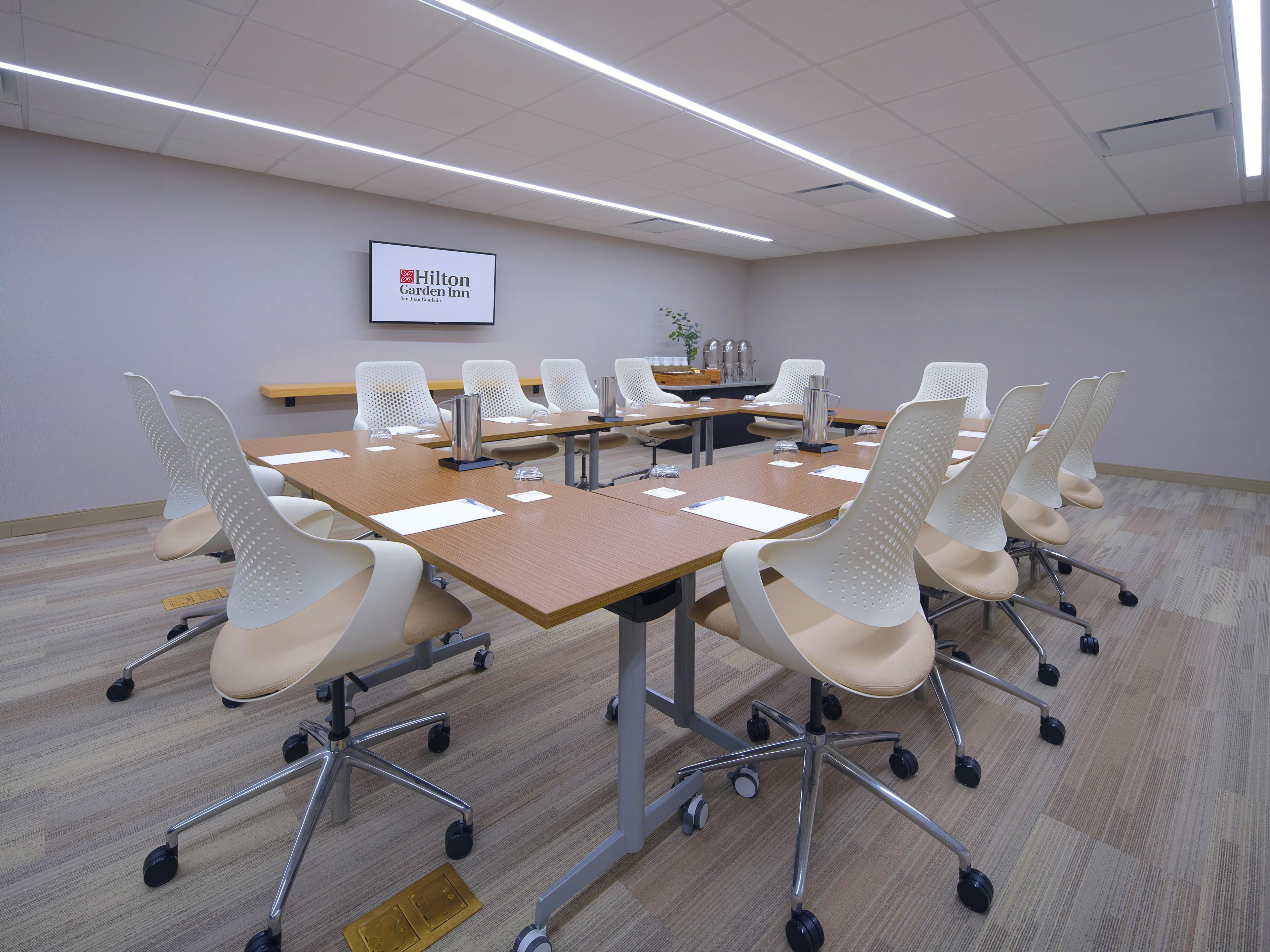A conference room with a long table, white chairs, and a sign for Hilton Garden Inn.