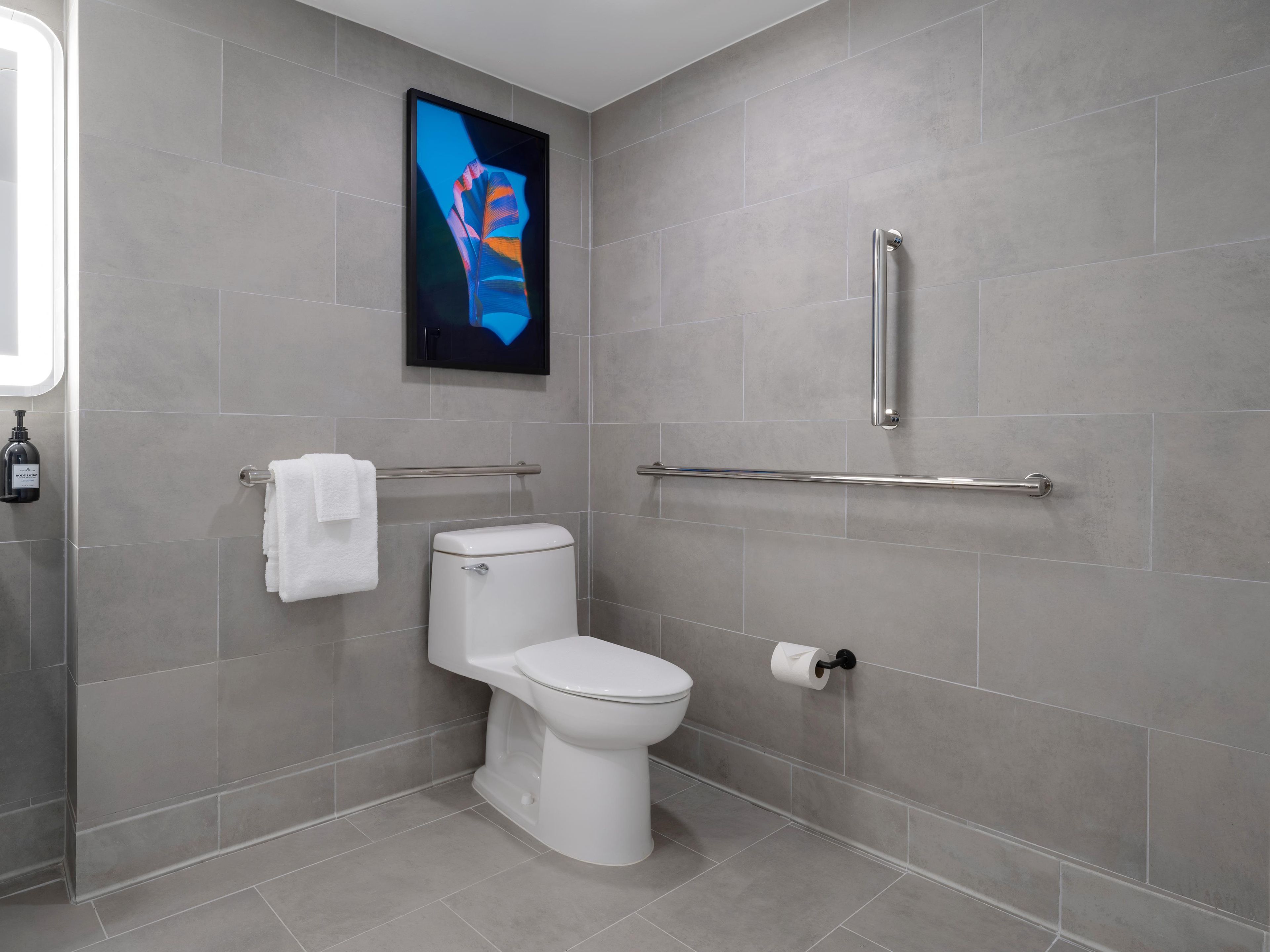 A modern bathroom with a toilet, a handrail, and a towel rack.