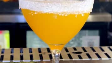 A margarita with salt rim in a martini glass on a bar counter.