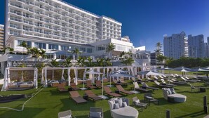 A hotel with multiple floors, outdoor seating areas, and palm trees. - Hilton Garden Inn San Juan Condado (San Juan)