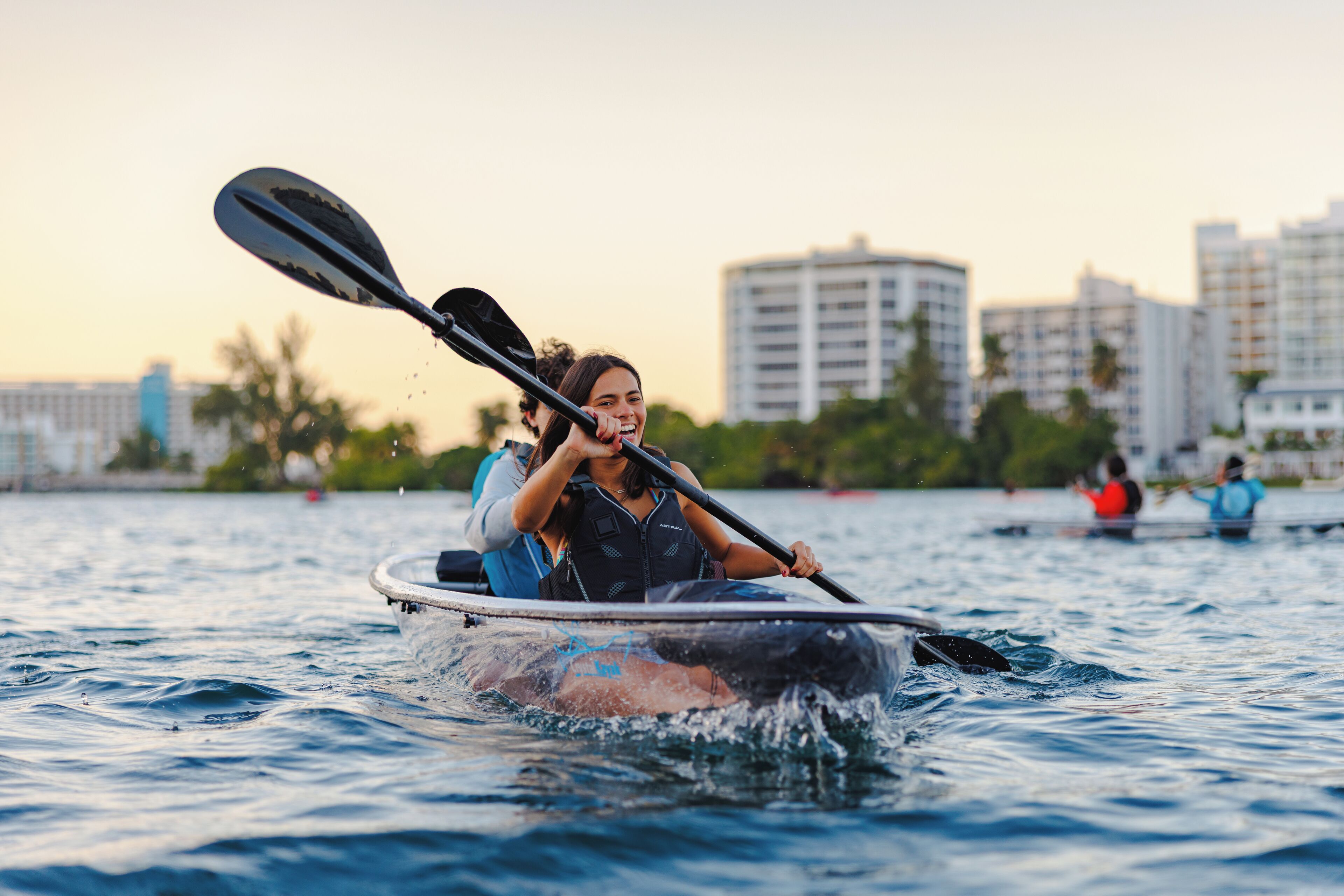 A kayak on calm water with a city skyline in the background.