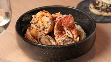 A bowl of cooked seafood, possibly lobster, on a wooden table.