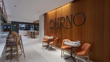 Un interior moderno con una pared de madera que muestra el nombre 'OHRNO' y una zona de estar con mesas y sillas.