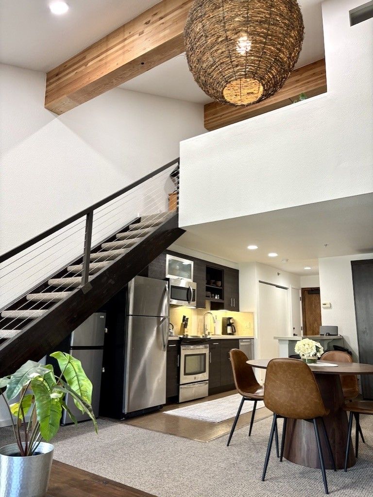 A modern kitchen with a built-in refrigerator, a dining area with a table and chairs, and a staircase connecting two levels.