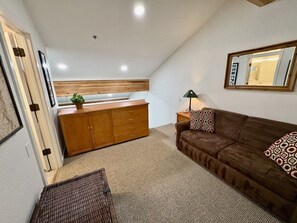 Un salon chaleureux avec un canapé marron, un meuble en bois et une petite table sur laquelle se trouve une lampe.