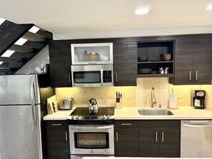 A modern kitchen with dark cabinetry, stainless steel appliances, and a built-in microwave.