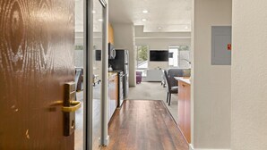 A hallway leading to a kitchen area with a refrigerator, stove, and a flat-screen TV mounted on the wall. - 354 | Premium Loft Vibes - Oven, A/C + Pool (Olympic Valley)