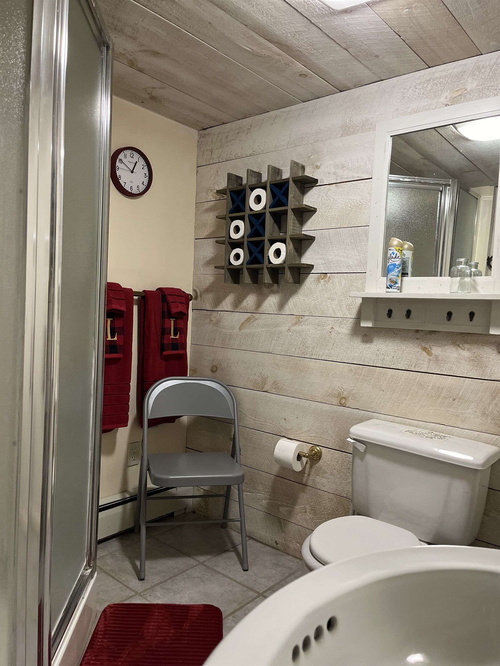 A bathroom with a toilet, a sink, a mirror, and a wall-mounted toilet paper holder.