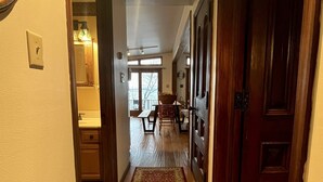 A hallway with a patterned carpet, wooden doors, and a dining area in the background. - Lion View ~ Otsego Lake ~ Sleeps up to 10 (Cooperstown)