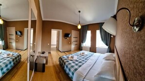 A hotel room with two beds, a desk, a chair, a TV, and a mirror. - Varga Kvareli (Kvareli)