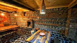 A rustic interior with a stone floor, wooden walls, a stone fireplace, and a hanging light fixture. - Varga Kvareli (Kvareli)
