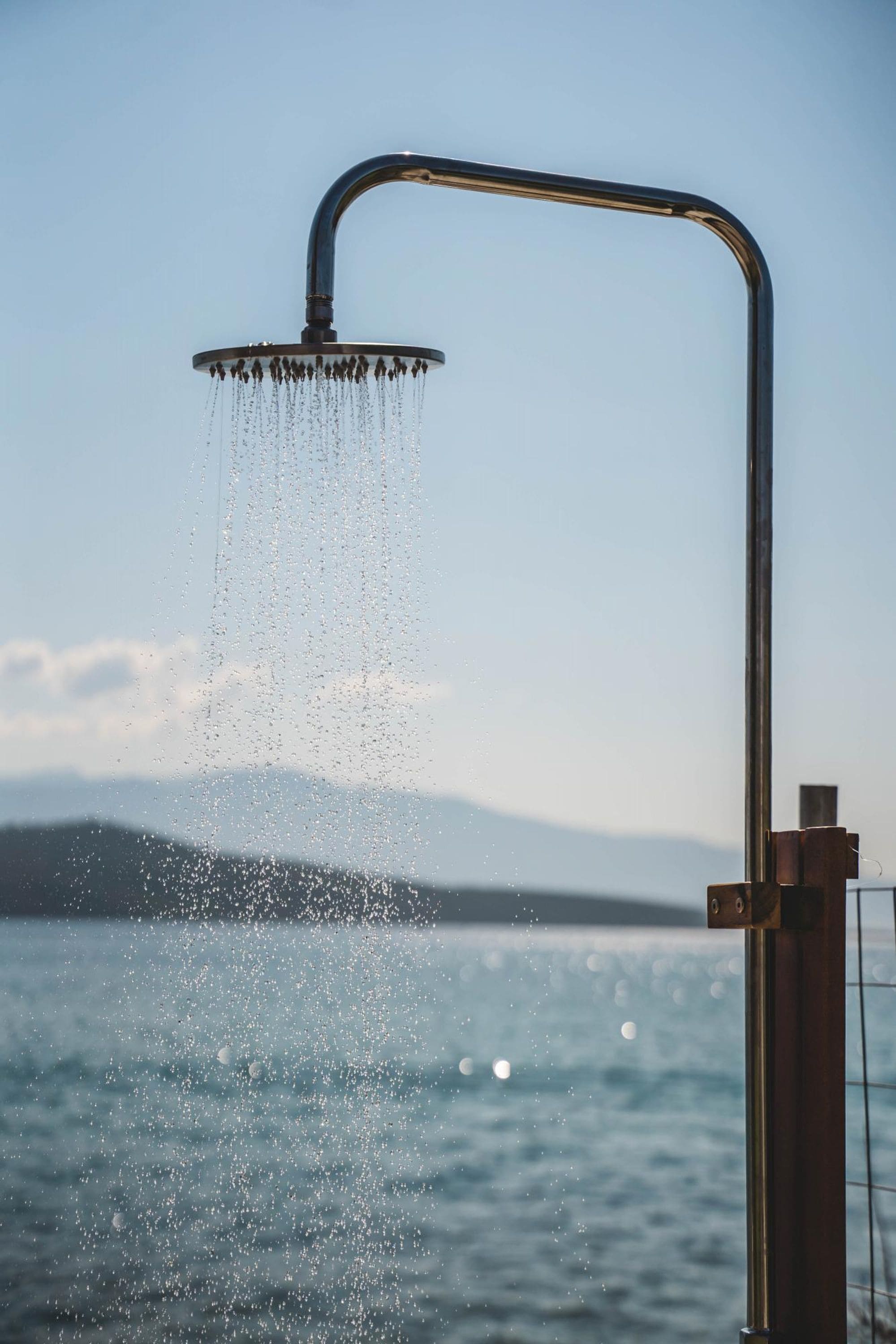 A showerhead over a body of water with a mountainous backdrop.