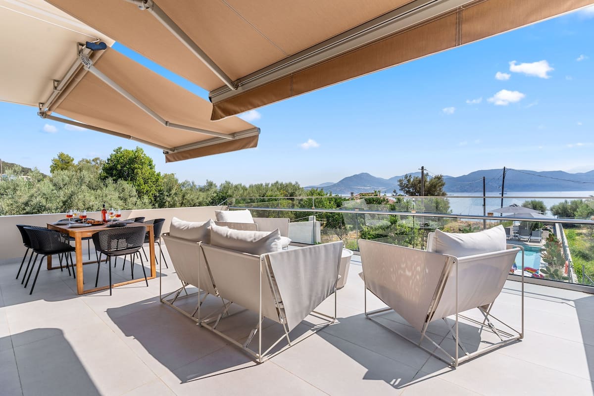 A terrace with a table and chairs, a pool, and a view of mountains.