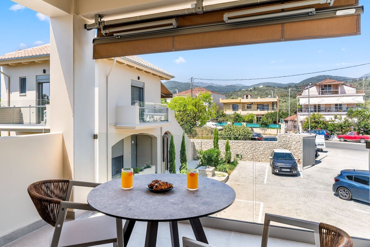 A balcony with a table, two chairs, and two glasses of orange juice.