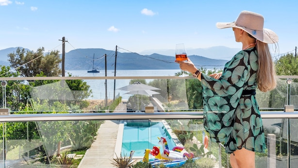 A person standing by a pool with a view of mountains and a body of water. - Blue Symphony Suites & Apartments (Lefkada)