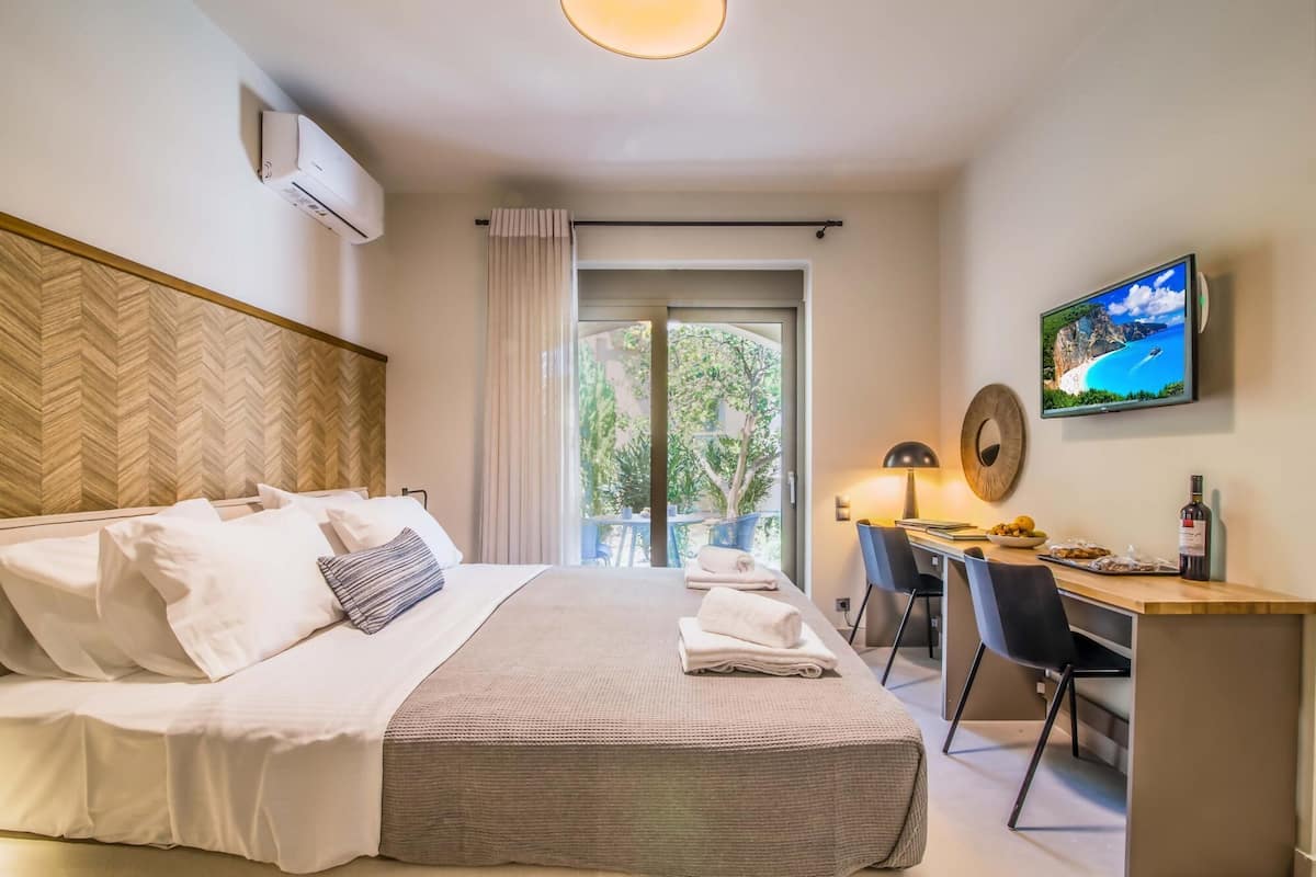 A hotel room with a bed, a desk, a TV, and a view of the outdoors.
