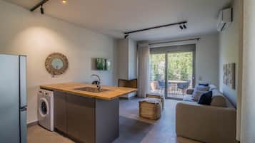 A modern kitchen with a built-in washing machine, a wooden countertop, and a large window overlooking a patio area.