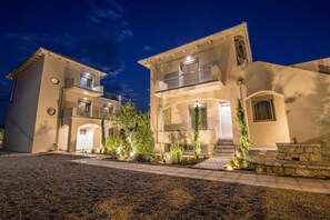 A modern two-story house with a well-lit entrance, a stone pathway, and a small garden area. - Blue Symphony Suites & Apartments (Lefkada)