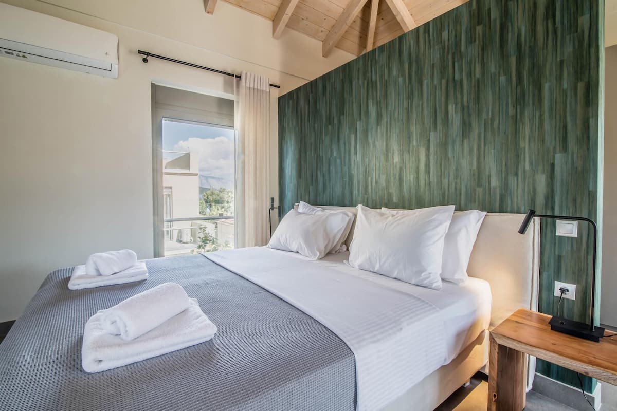 A hotel room with a large bed, two pillows, a bedside table, and a window with curtains.