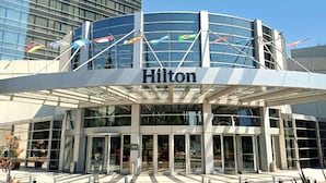 A modern Hilton hotel with a glass facade and a curved entrance. - Hilton Mendoza (Guaymallen)