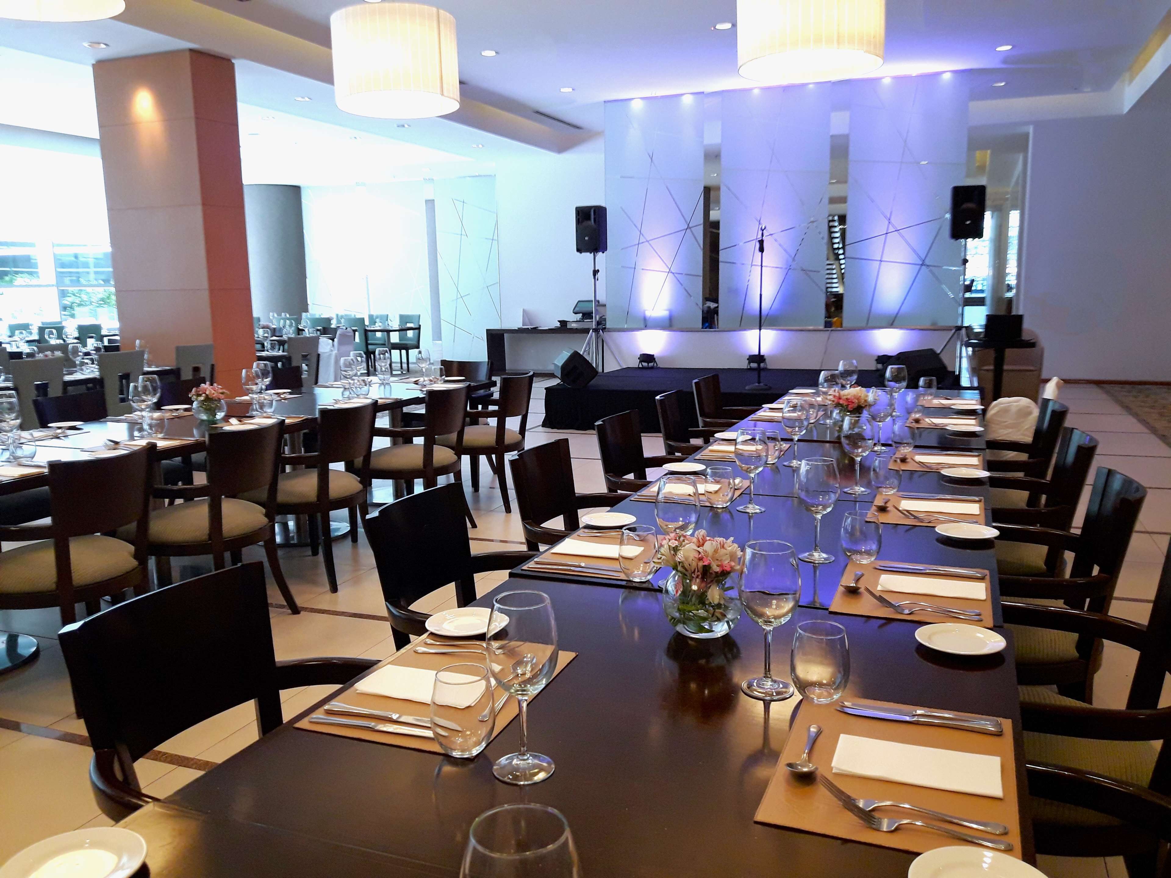 A large dining area with multiple tables set for a meal, equipped with wine glasses, plates, and cutlery.