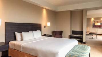 Una habitación de hotel con una cama grande, un escritorio, una silla y una mesita.