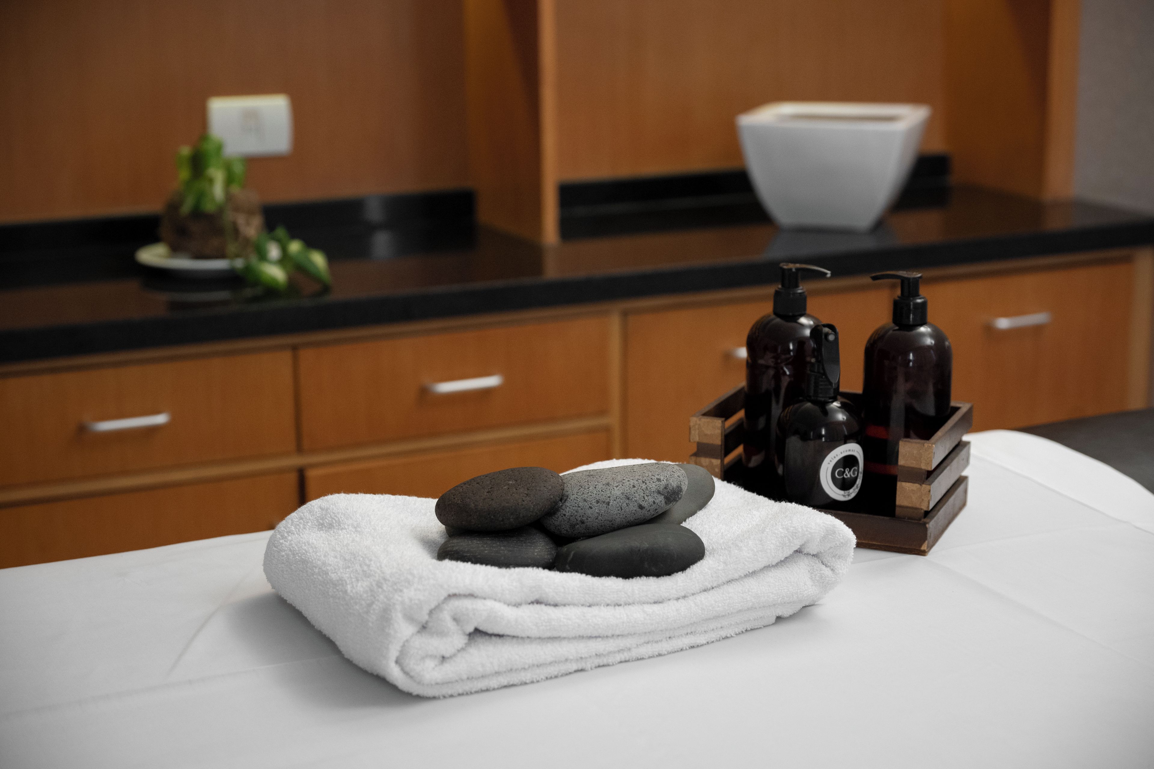 A neatly arranged bathroom with a towel, stones, and toiletries on a counter.