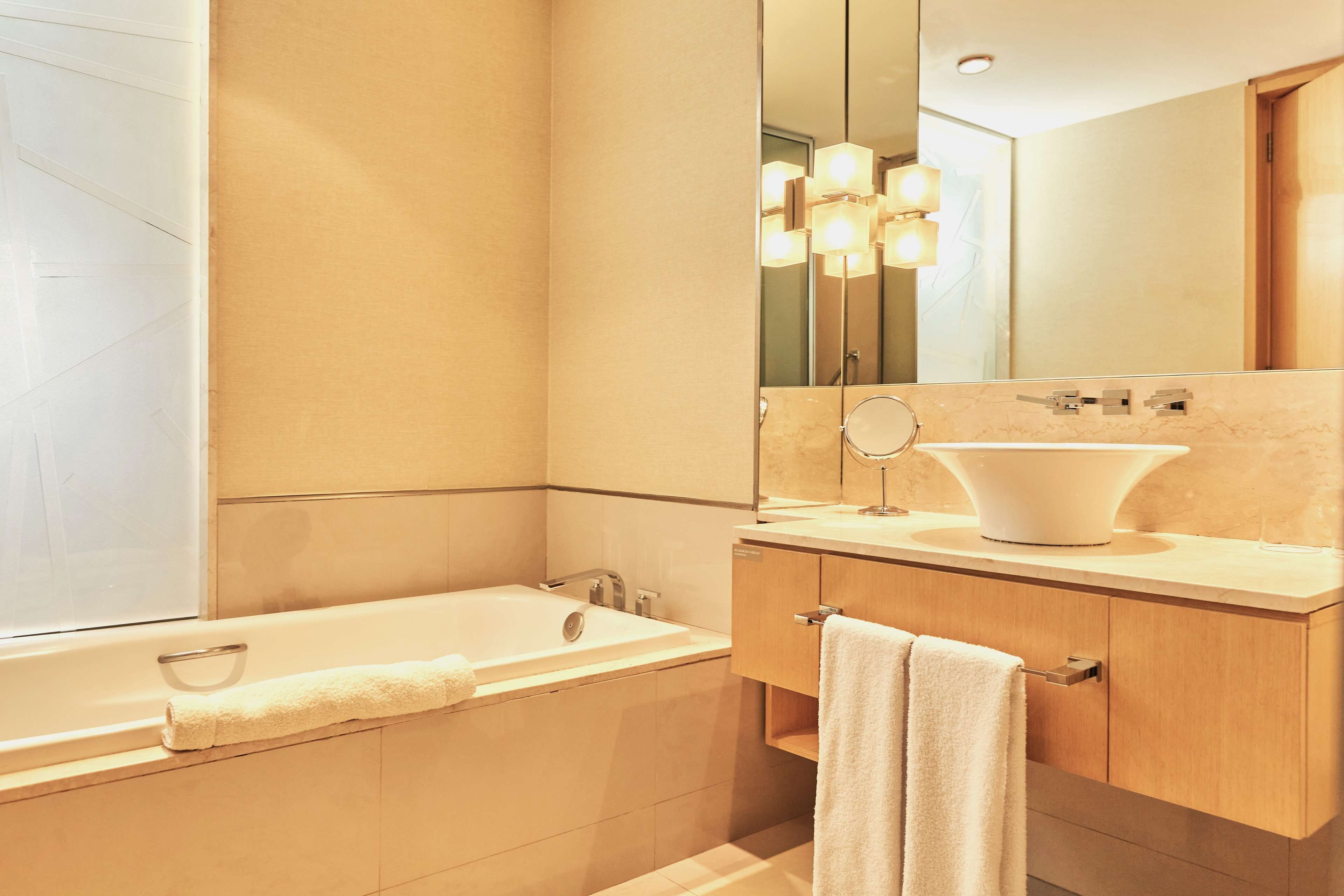 A modern bathroom with a bathtub, a sink, a vanity, and a large mirror.