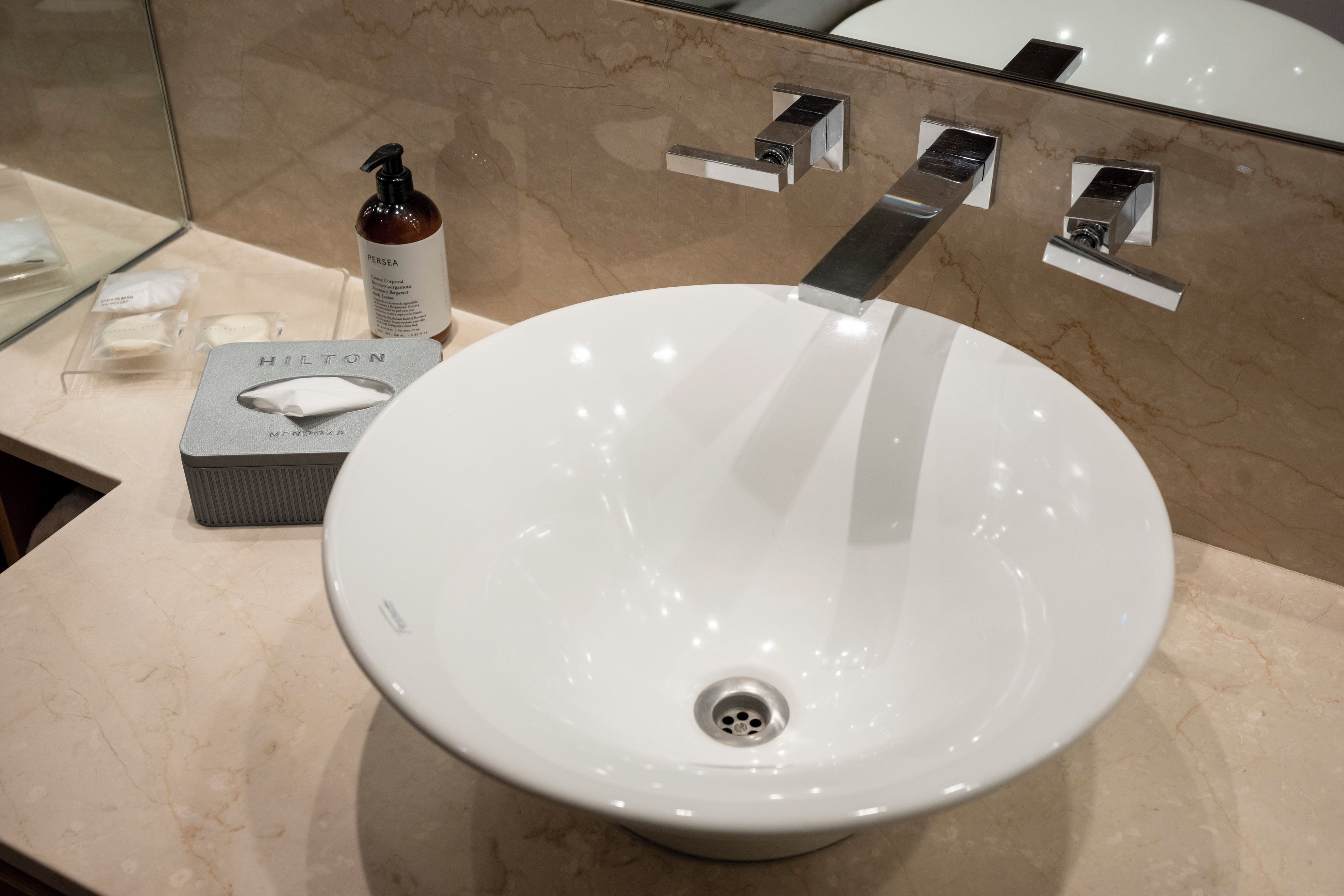 A bathroom with a white sink, a mirror, and toiletries.