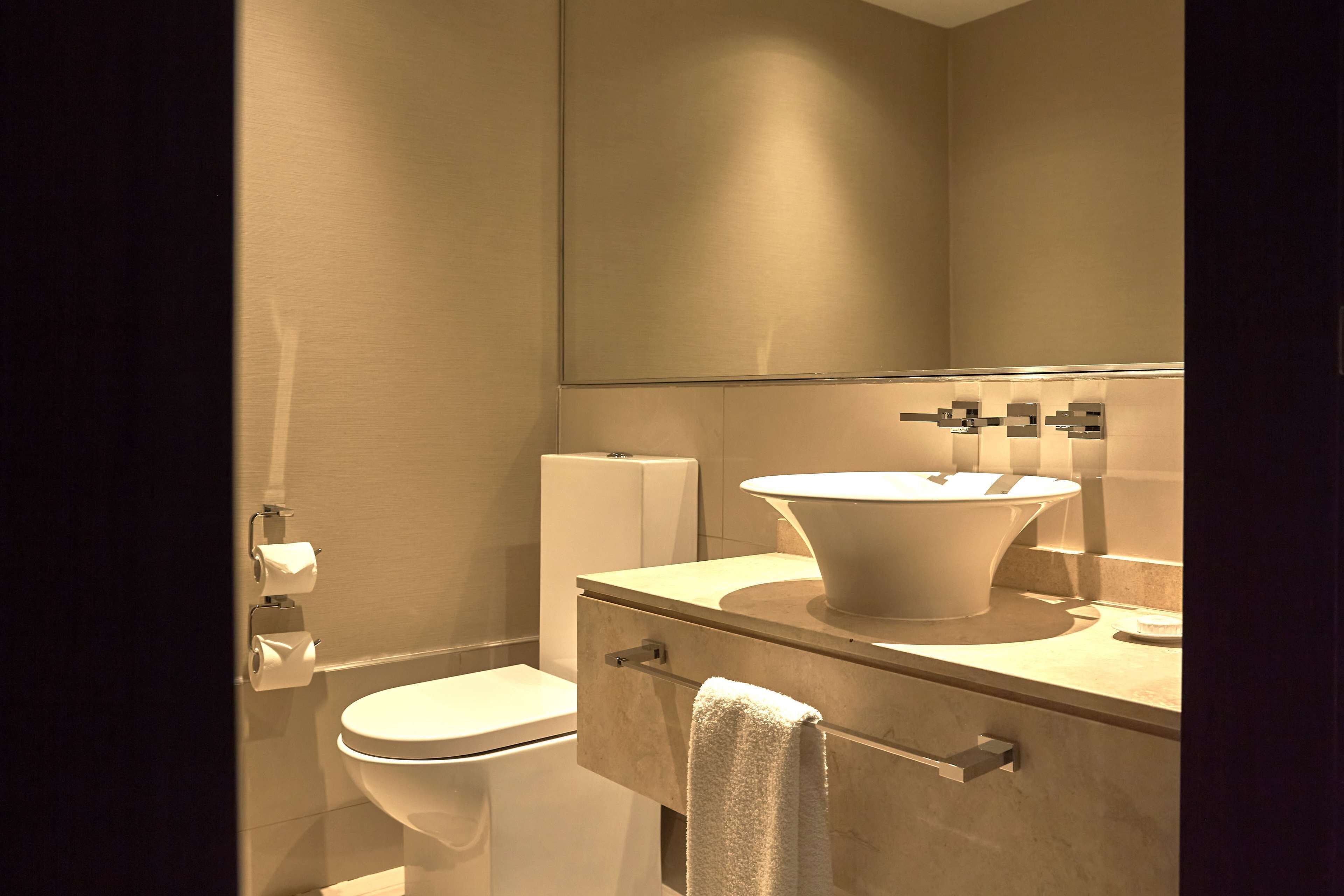Un baño moderno con inodoro, lavamanos y espejo.