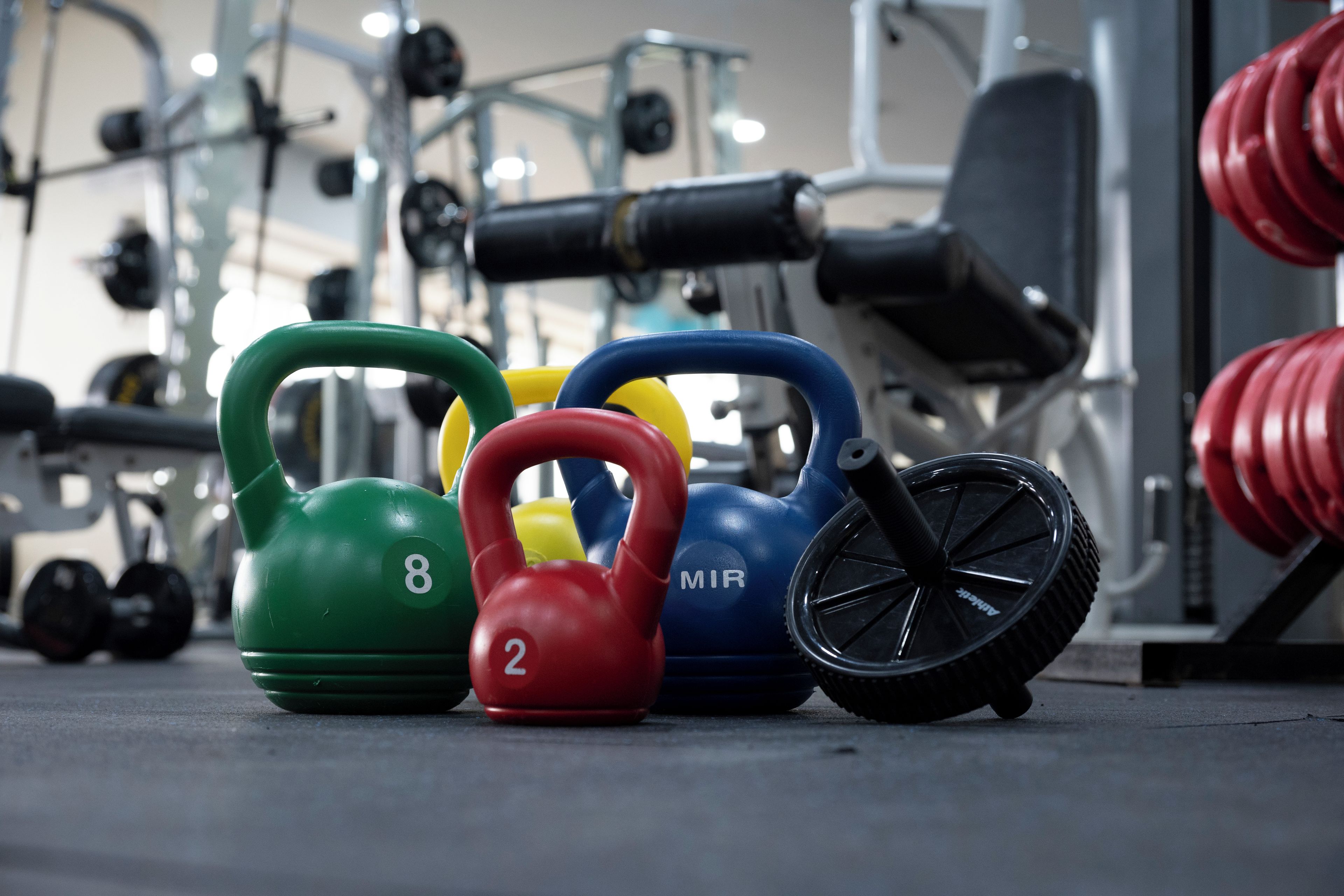 A set of kettlebells with numbers and letters on them, placed on a gym floor.