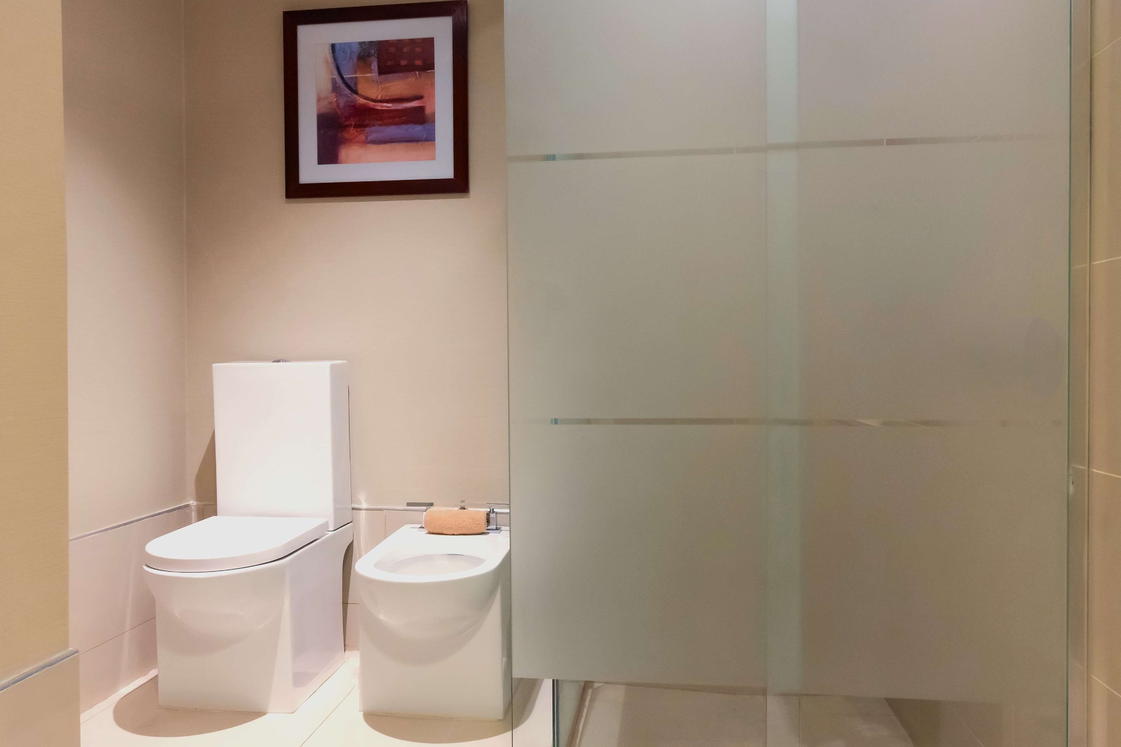 Een moderne badkamer met toilet, bidet en douchecabine van glas.