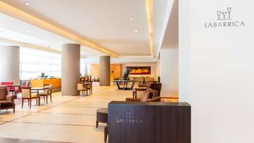 A spacious lobby with a reception desk, seating areas, and a large window providing natural light.