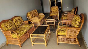 A room with wicker furniture, including sofas and a coffee table, arranged around a central area. - Serene Hostel Accra Bunk Bed Mixed dormitory (Adenta Municipality)
