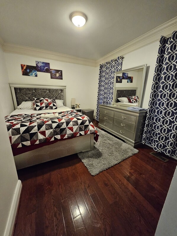 A bedroom with a bed, dresser, and a mirror.
