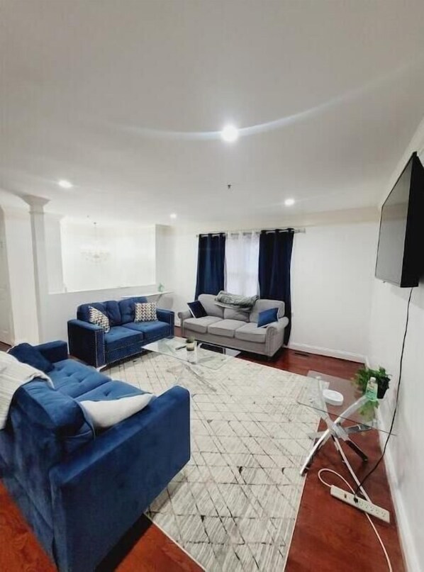 Uma sala de estar moderna com dois sofás, uma mesa de centro e uma TV fixada na parede.