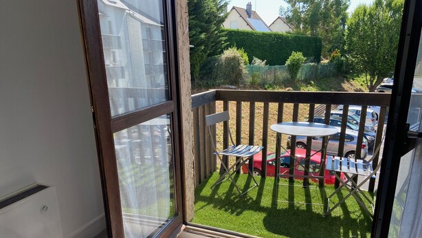 A balcony with a view of a red car and a green lawn. - Spacious T3 with balcony - close to town center (Touques)