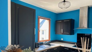 A modern kitchen with black cabinets, a wooden countertop, and a window with a view of a building. - Spacious T3 with balcony - close to town center (Touques)