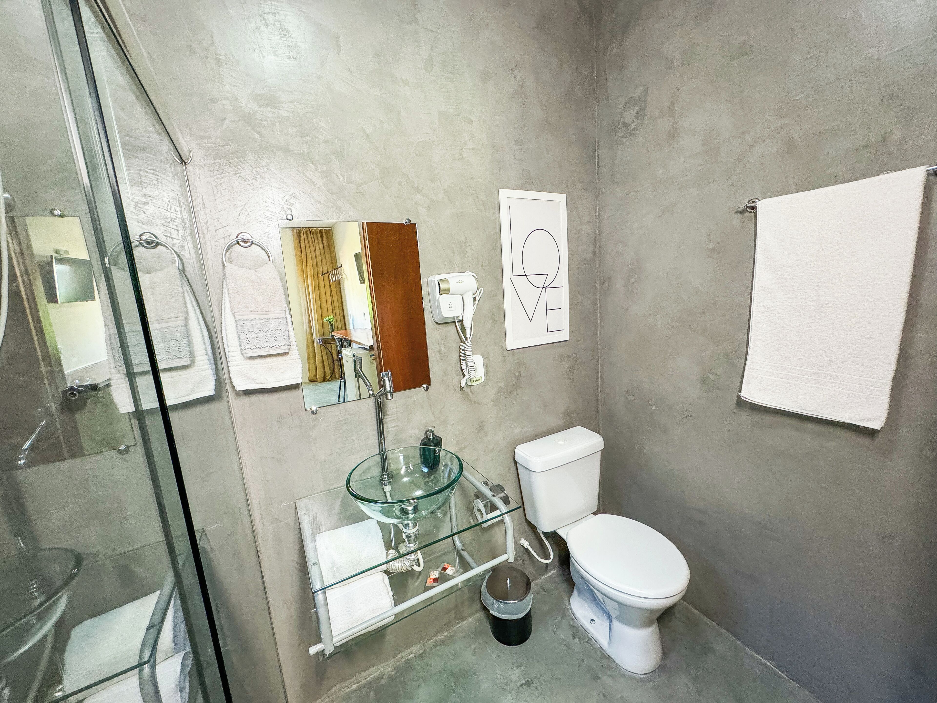 A bathroom with a glass sink, white toilet, and a towel rack.